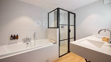 Un baño moderno con ducha envuelta en vidrio, una bañera amplia y un lavamanos.