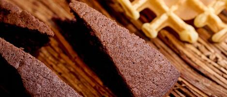 A wooden cutting board with waffles and slices of brown bread.