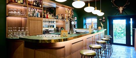 A bar area with wooden cabinets, bar stools, and a variety of bottles and glasses.