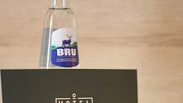 Una botella de vidrio con un logo de ciervo y el texto "BRU" sobre una caja negra con un logo de hotel.