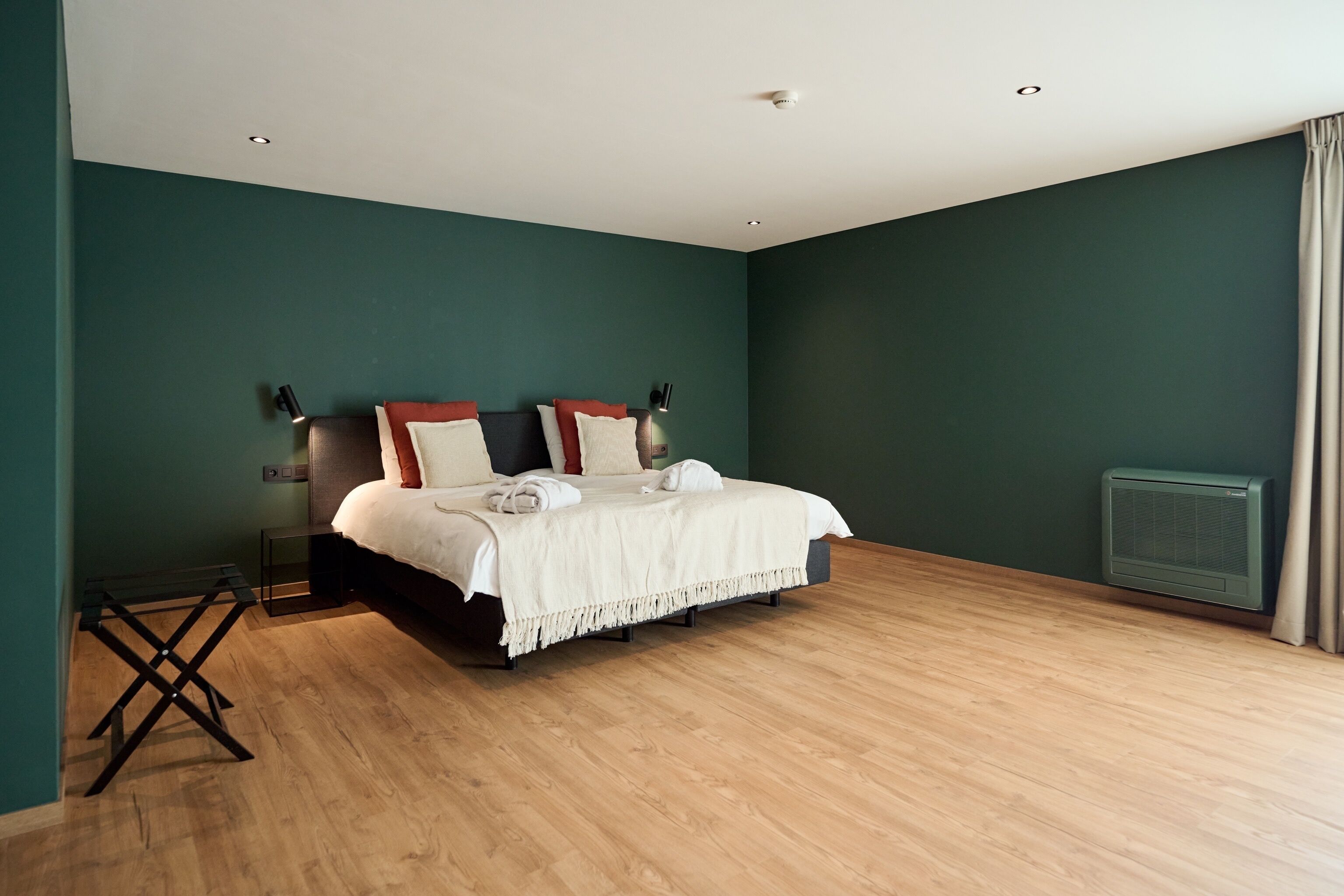 A bedroom with a bed, a standing lamp, and a heater.