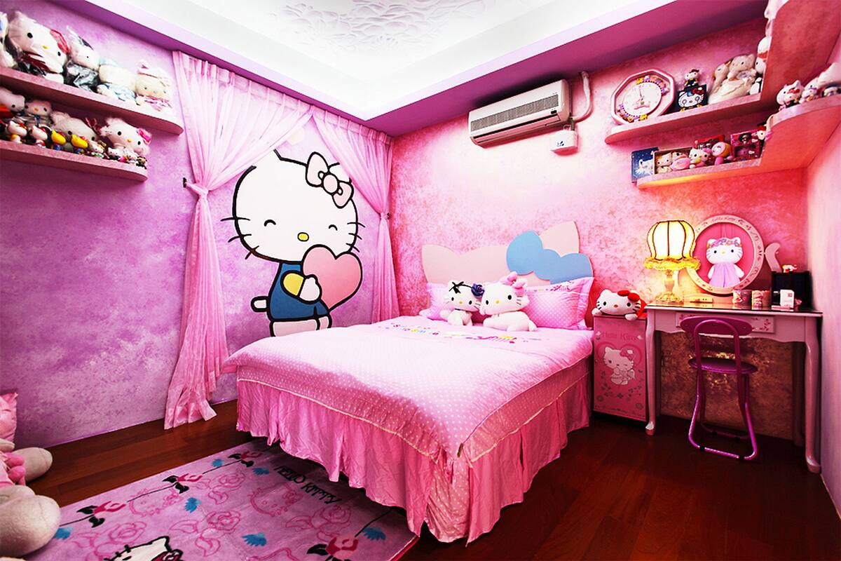 A pink-themed bedroom with a bed, a desk, and shelves with Hello Kitty items.