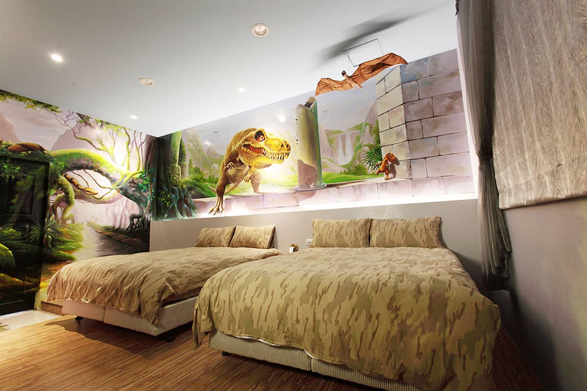 A bedroom with two beds, a mural of a dinosaur, and a stone wall.