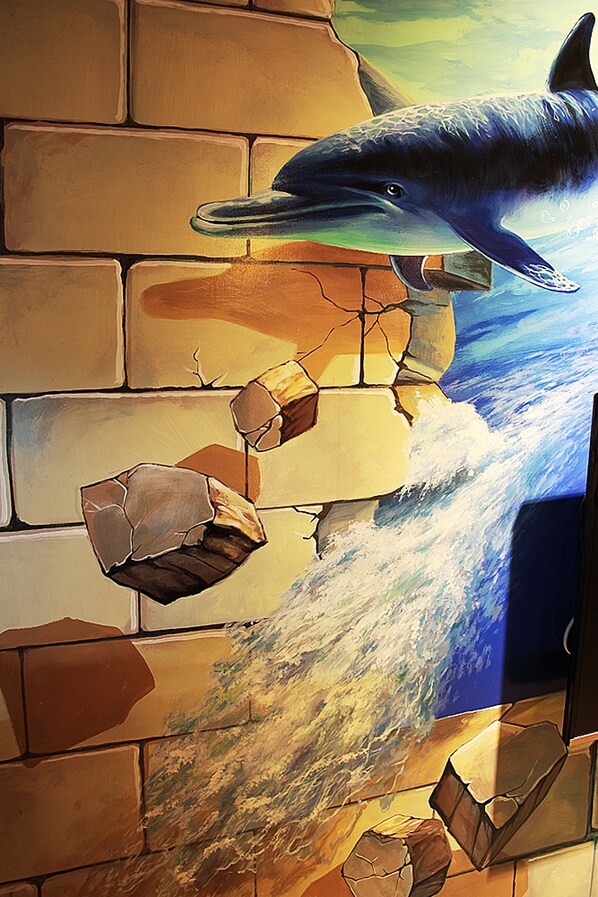 A dolphin swimming through a cracked wall, with water flowing through the cracks.