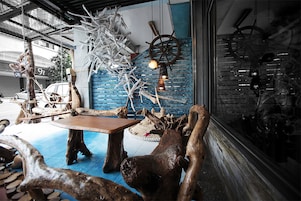 A rustic interior with wooden furniture and decor, including a table and chairs, a hanging light fixture, and a wheel wheel mounted on the wall.