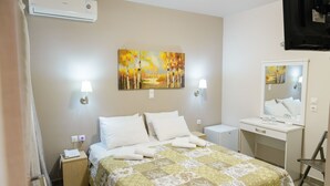 Habitación de hotel con cama, mesitas de noche, escritorio, silla, espejo y un cuadro en la pared.