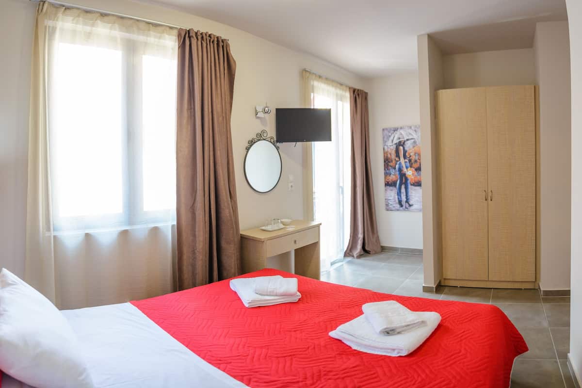 A hotel room with a bed, a TV, a desk, and a wardrobe.