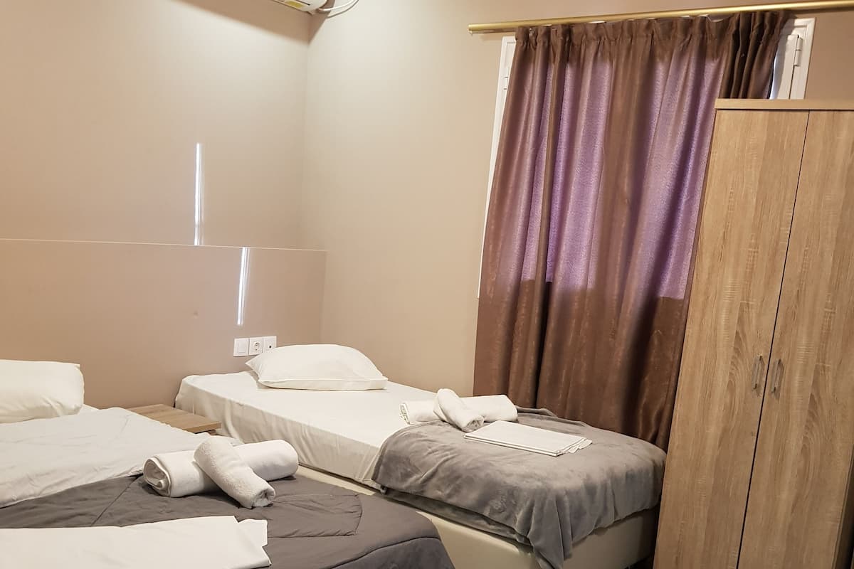 A hotel room with two beds, a wardrobe, and an air conditioning unit.