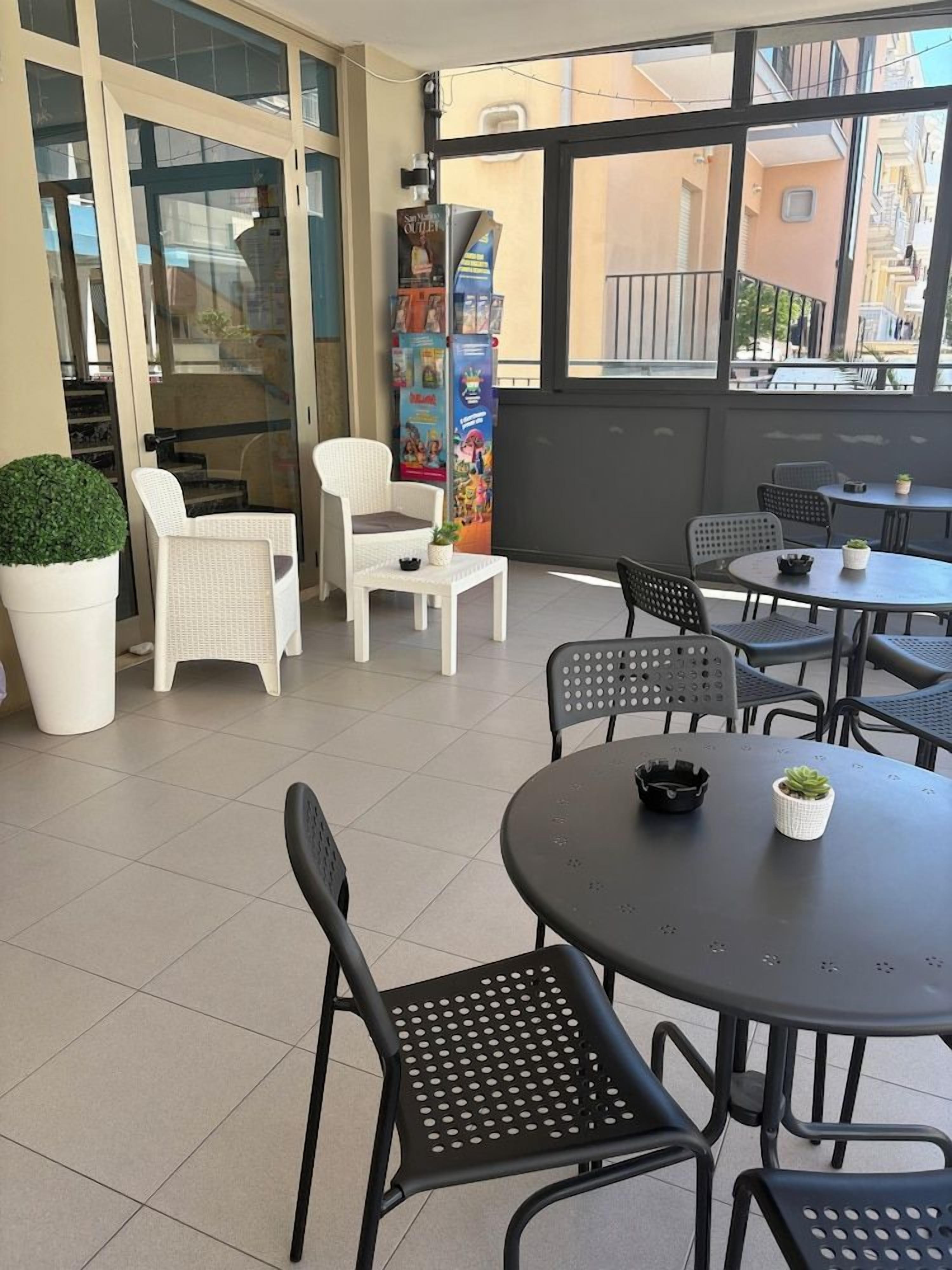 Una terrazza con posti a sedere all'aperto, tra cui tavoli e sedie rotonde, e un'ampia pianta in vaso.