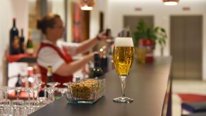 Um bar com uma caneca de cerveja, um barman e uma taça de nozes no balcão.