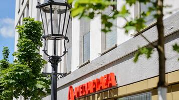 A building with a sign reading "AMEDIA PLAZA" and a street lamp.