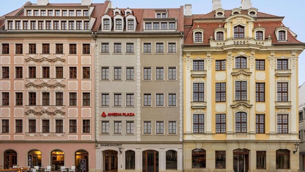 Uma fileira de edifícios históricos com estilos arquitetônicos distintos, incluindo fachadas elaboradas e janelas em arco.