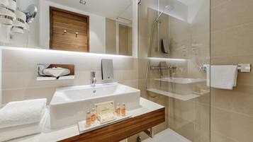 A modern bathroom with a large sink, mirror, and glass shower enclosure.