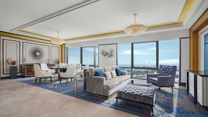 A spacious living area with a large window, a sofa, chairs, and a decorative fan.