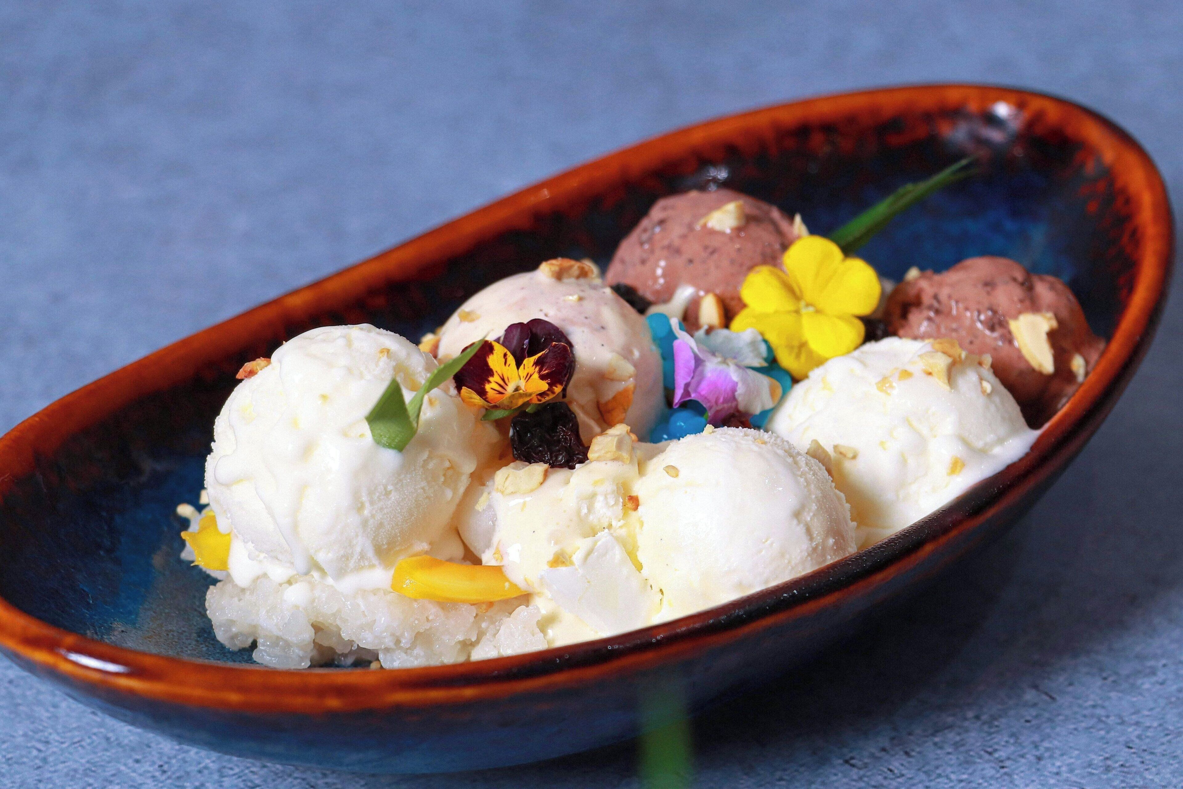 A bowl of ice cream with various toppings and a flower.