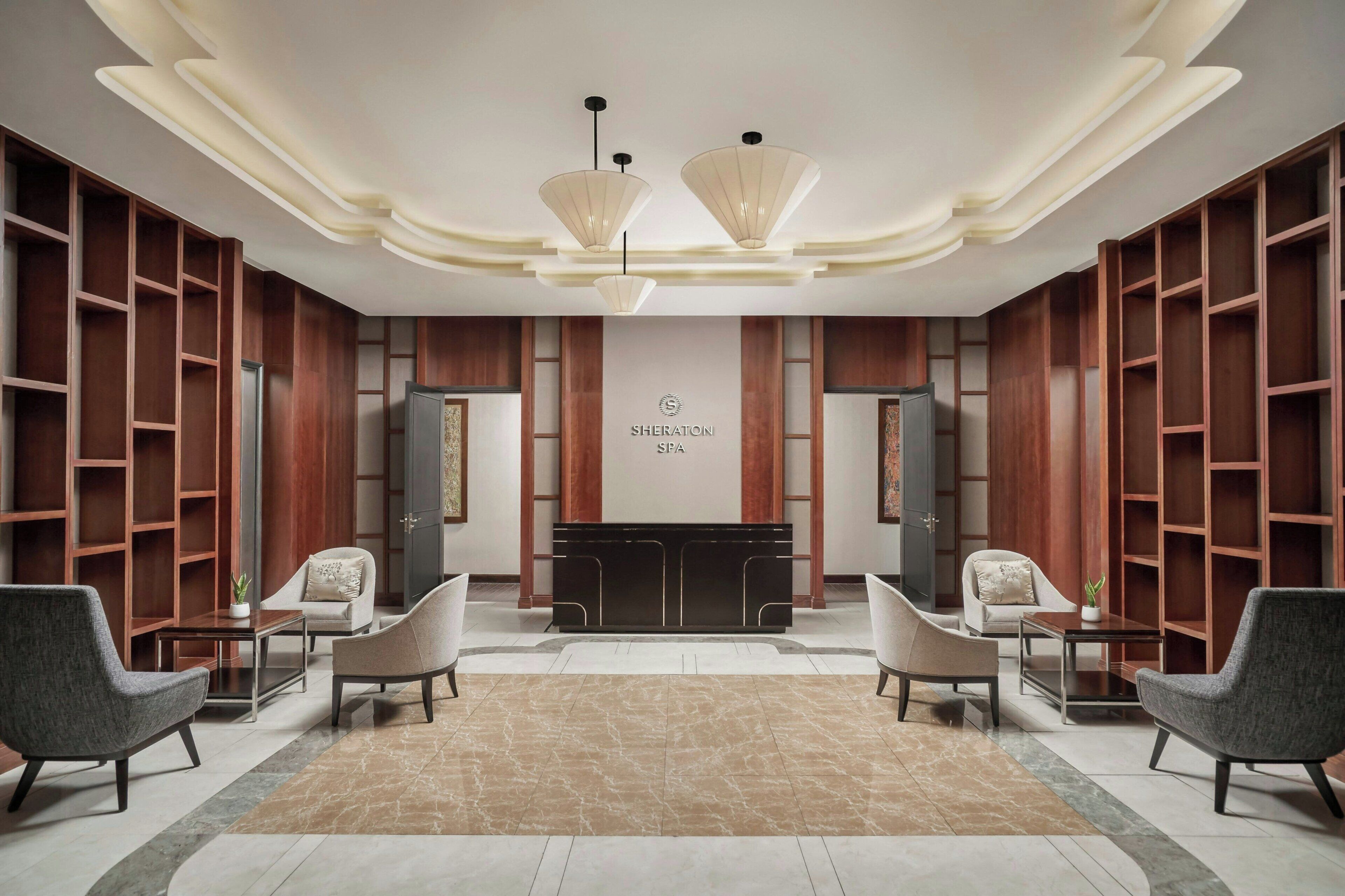 A modern lobby with a reception desk, two sofas, and wooden shelving.