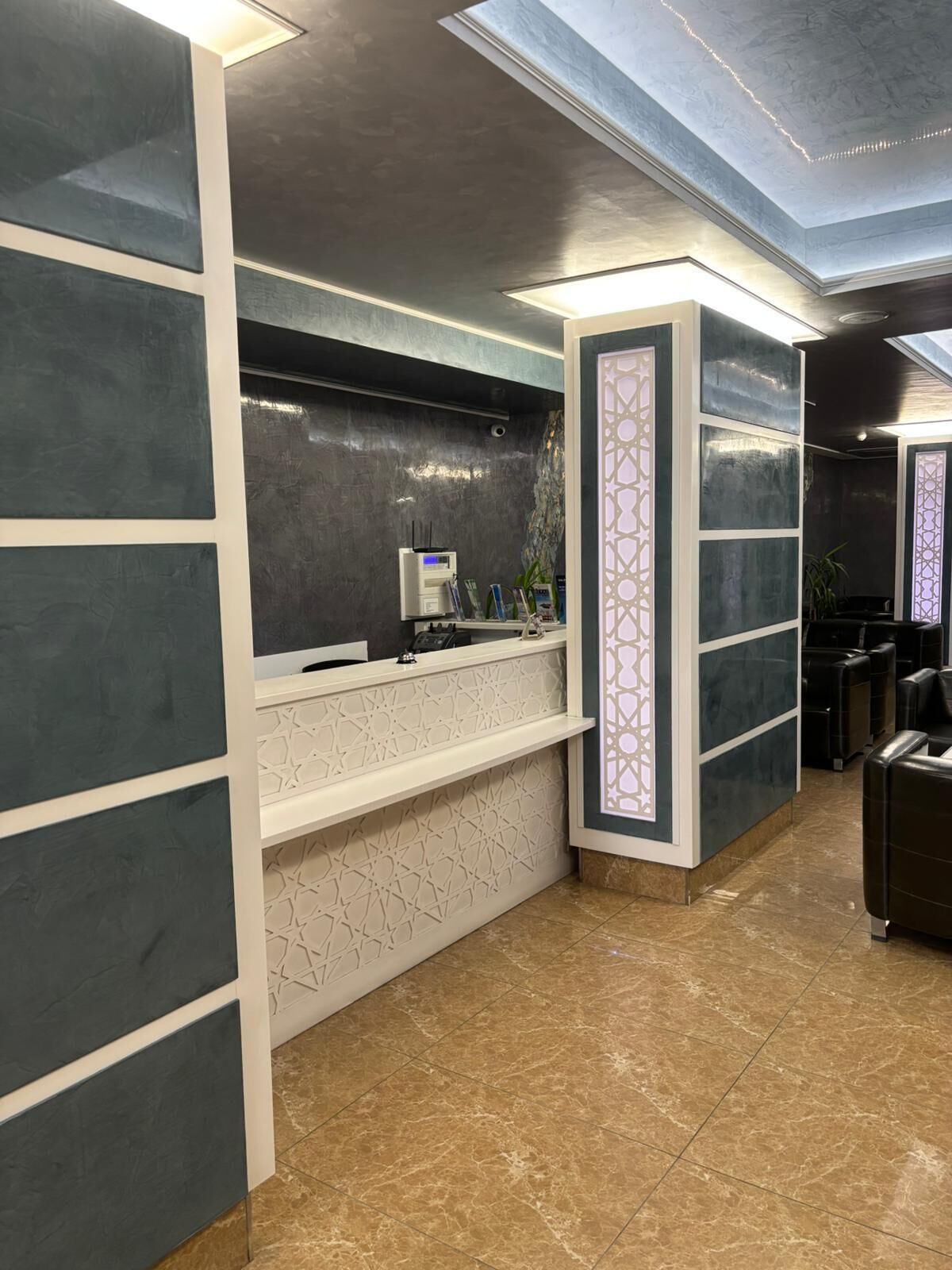 A reception area with a counter, a digital display, and a seating area with leather chairs.