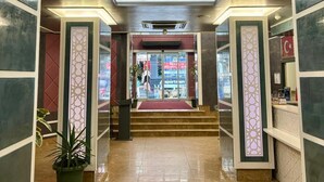 Un vestíbulo de hotel con una escalera central, una recepción y una zona de estar.