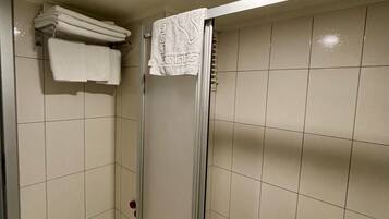 En dusch med en glasdörr, kaklade väggar och en taklampa.