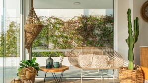 A modern balcony with wicker furniture, a cactus plant, and a view of a lush garden wall. - Blue Harbour Boutique (Ayia Napa)