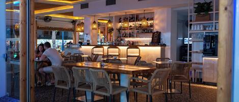 Ein Restaurant mit einer Holztheke, mehreren Sitzbereichen und unterschiedlichen Stühlen.