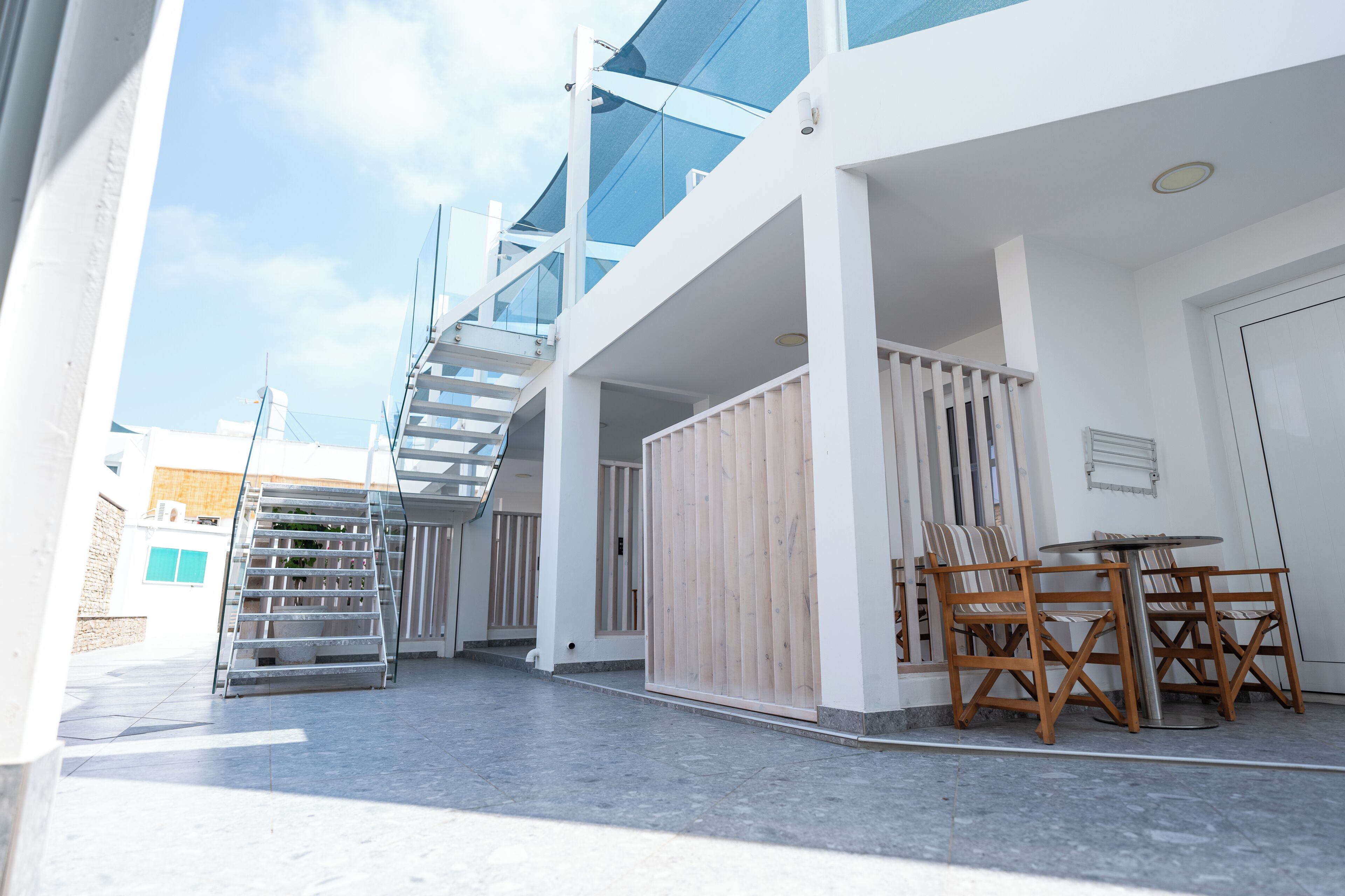 A modern outdoor area with a staircase, a wooden fence, and a table with chairs.