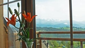 Une table ornée d’un vase de fleurs et d’une tasse, placée sur un balcon offrant une vue sur la montagne.