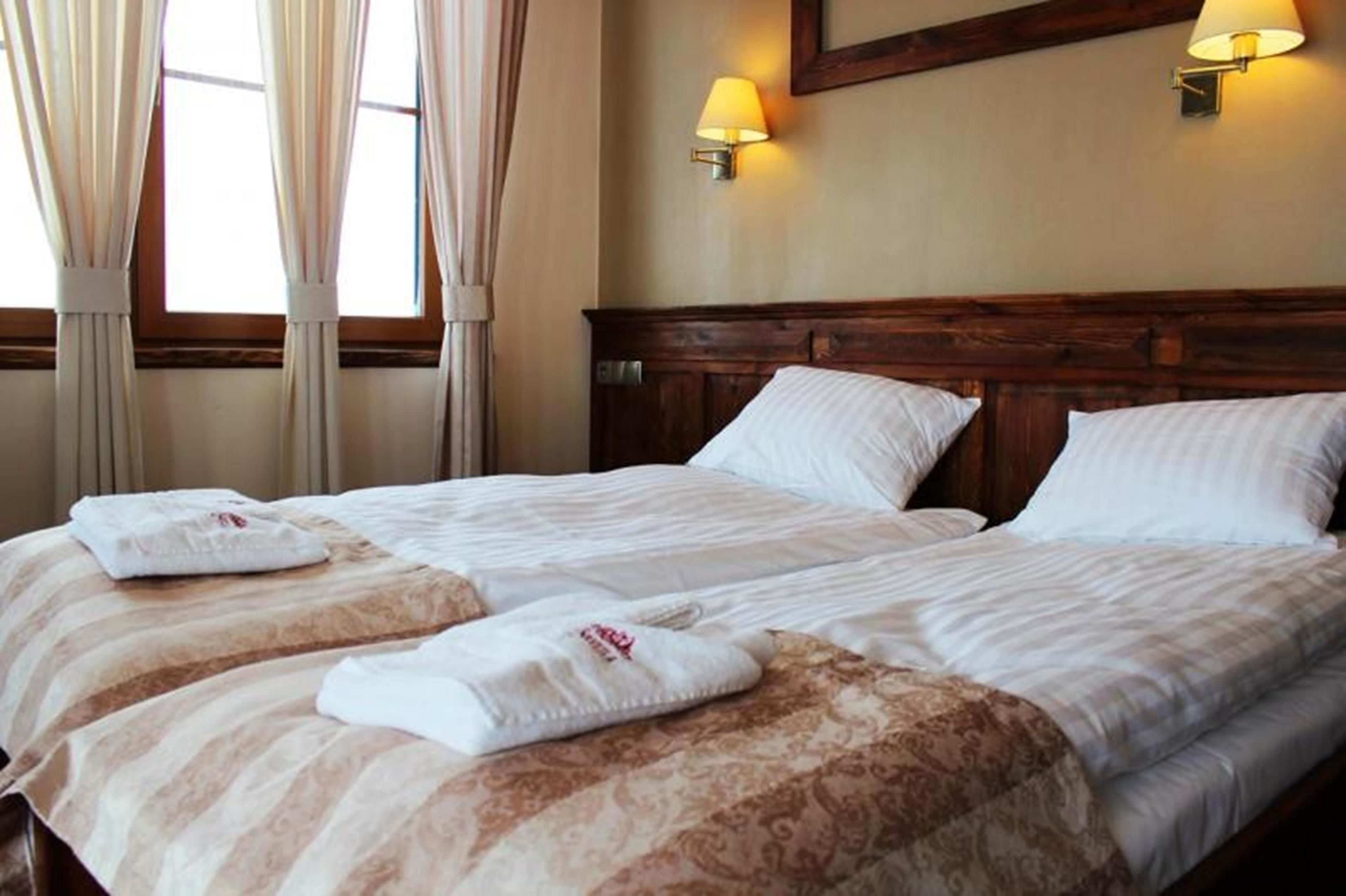 Ein Hotelzimmer mit einem großen Bett, zwei Kissen, einem Kopfteil und zwei Wandlampen.
