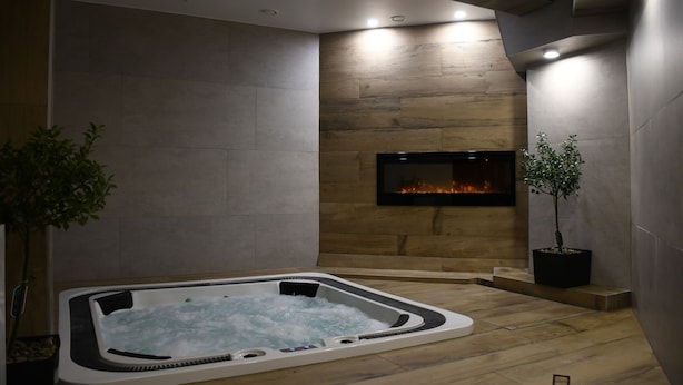 Une salle de spa moderne dotée d’un jacuzzi, de planchers en bois et d’une cheminée.
