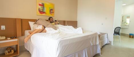 A hotel room with a bed, a nightstand, a chair, and a mirror.