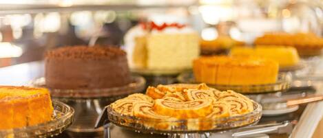 A display of various cakes on glass stands in a bakery.