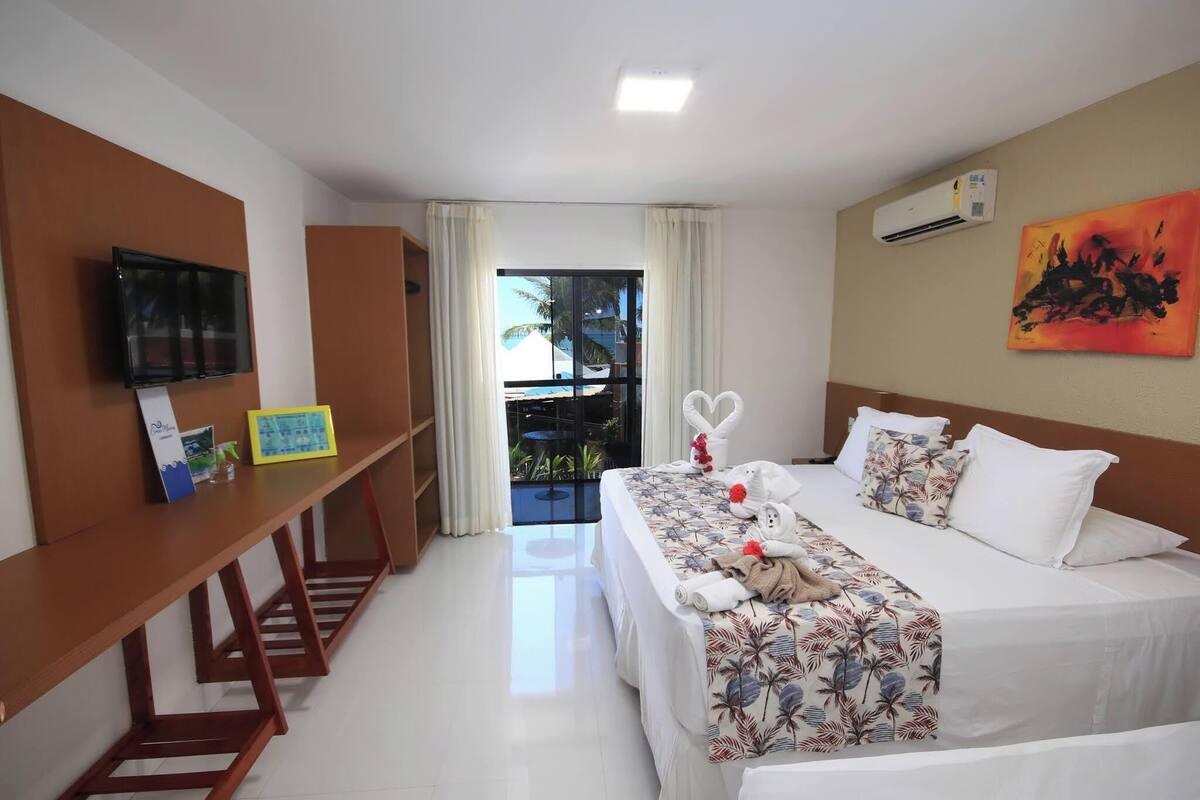 A hotel room with a bed, a desk, a TV, and a window with curtains.