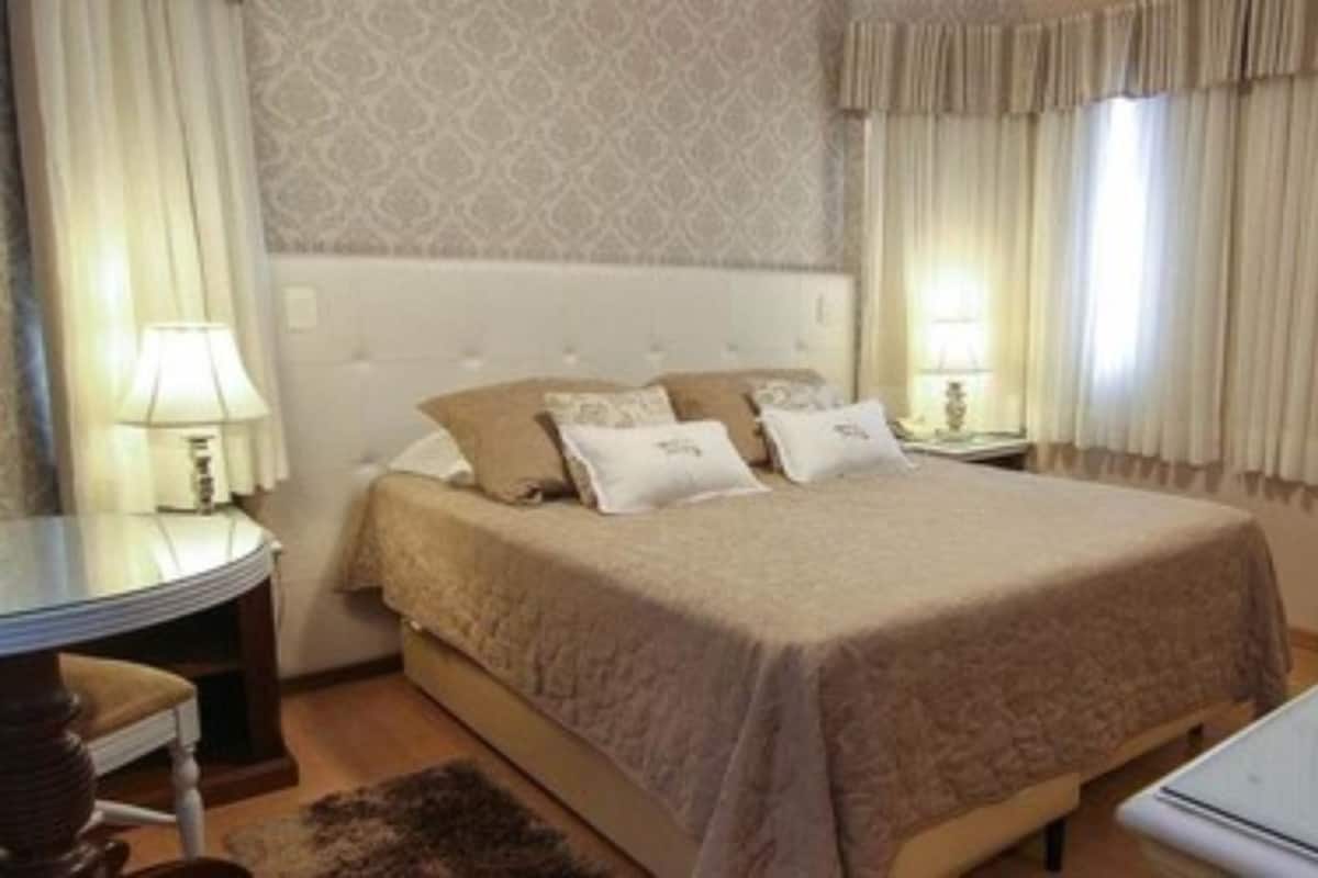 Une chambre d’hôtel avec un lit, des tables de chevet, un bureau et un radiateur.