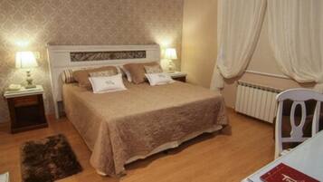 A bedroom with a bed, two bedside tables with lamps, a radiator, and a chair.