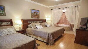 Une chambre d’hôtel avec deux lits, un coin salon avec un canapé, une télévision et une baignoire.