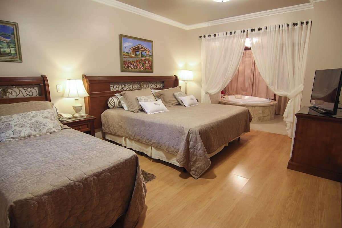 Une chambre d’hôtel avec deux lits, un coin salon avec un canapé, une télévision et une baignoire.