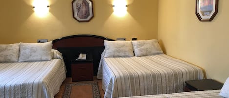 A hotel room with two beds, a nightstand, a telephone, and two wall-mounted lights.