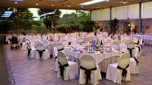 A banquet hall with round tables covered in white tablecloths, each surrounded by chairs with black sashes. - Hotel Sena (Caldas de Reis)