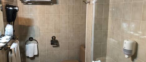 Une salle de bain équipée d’un lavabo, de toilettes et d’une douche. Des serviettes et des articles de toilette sont accrochés au mur.