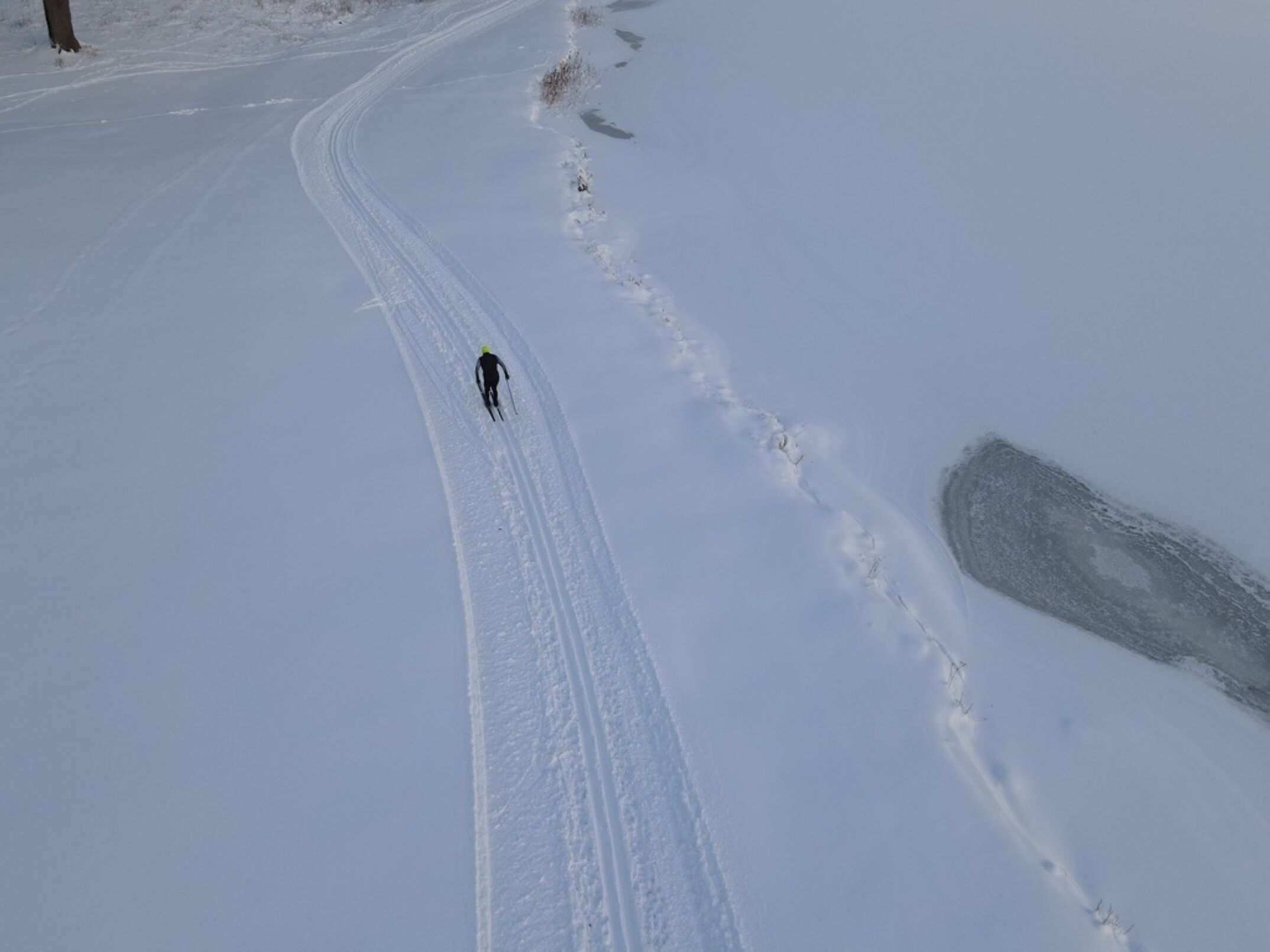 Eine verschneite Landschaft mit einem einzelnen Skifahrer auf einer klaren Piste.