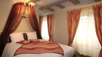 Une chambre à coucher avec un lit à baldaquin, un dais et des rideaux ornés de motifs floraux.