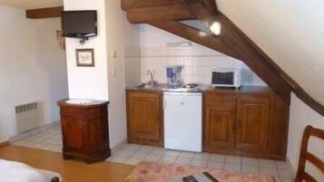 Una cocina pequeña y acogedora con armarios de madera, un refrigerador blanco, un microondas y un lavamanos.