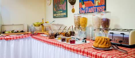 A buffet table with various food items and a cake, a vintage toaster, and a poster on the wall.