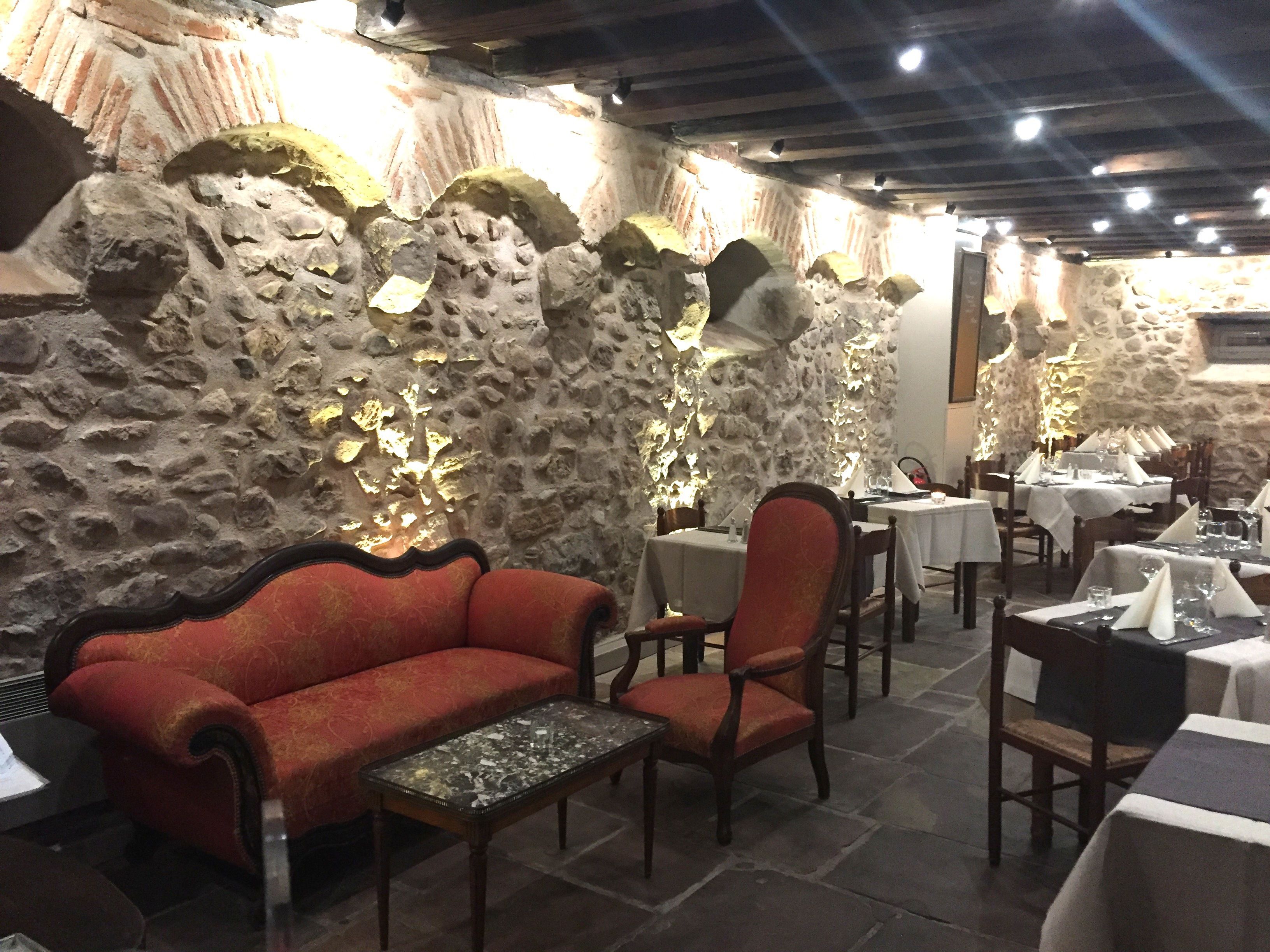 Ein Restaurant mit Steinsälen, Holzmöbeln und gedeckten Tischen.