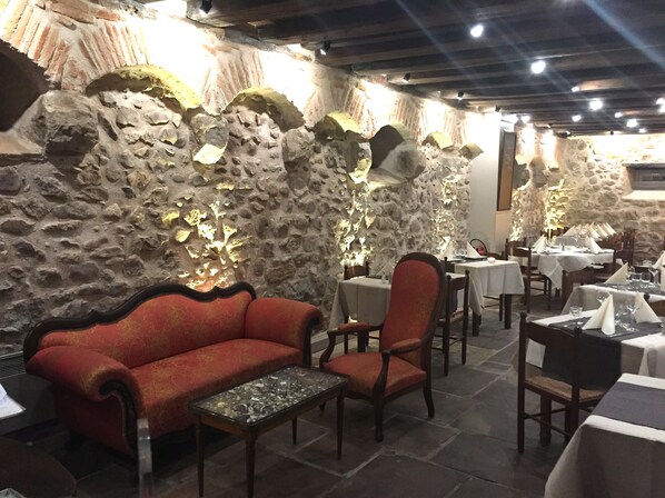 Un restaurante con paredes de piedra, muebles de madera y mesas dispuestas para comer.