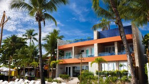A hotel with a pool area, palm trees, and a two-story building with balconies.