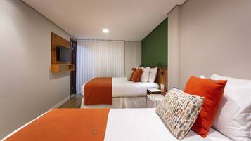Habitación de hotel con dos camas, un televisor en un estante y una pared de acento verde.