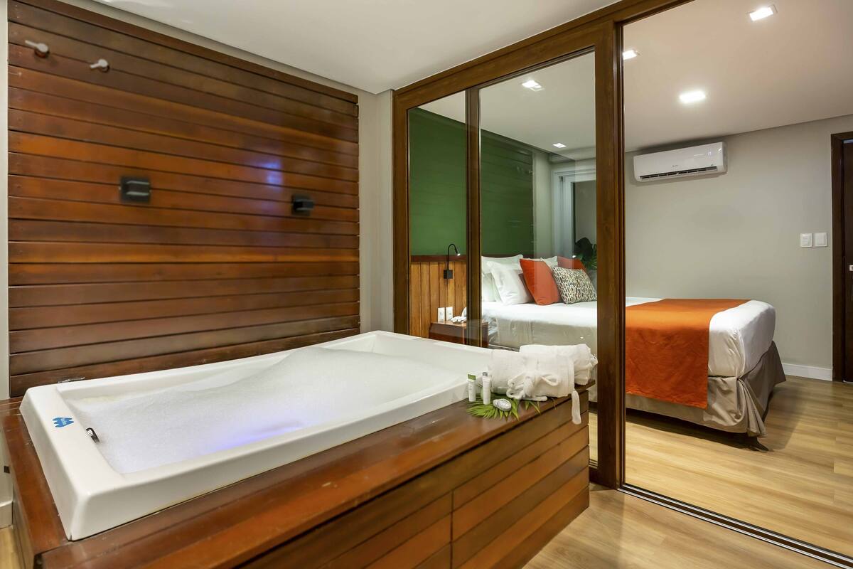 Un baño moderno con tocador de madera, bañera y un espejo grande.
