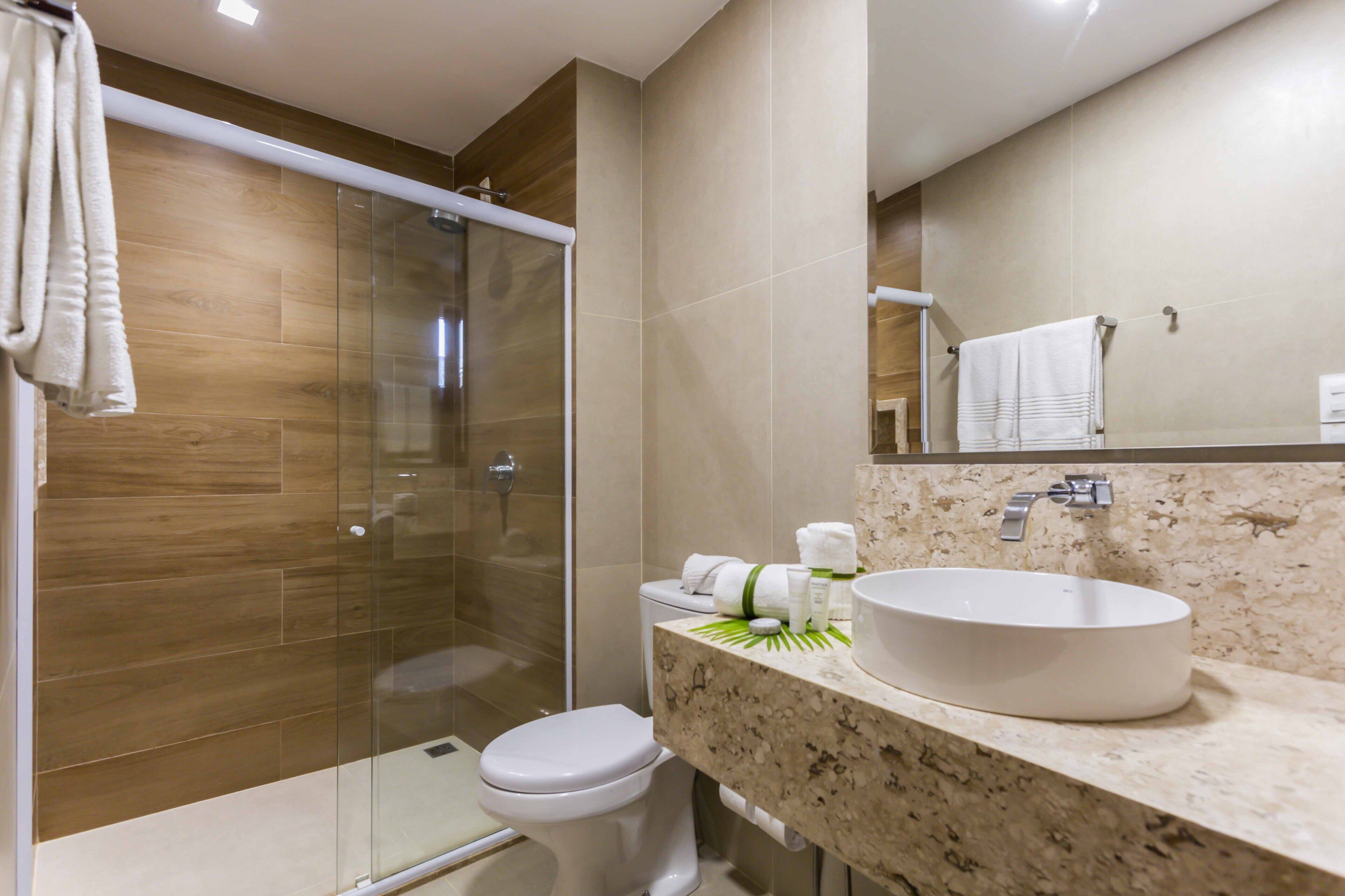 A modern bathroom with a glass shower enclosure, a white toilet, and a marble countertop with a sink.