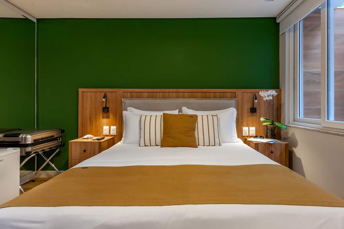 Una cama bien hecha con ropa de cama blanca y marrón, un cabecero de madera y lámparas de noche.